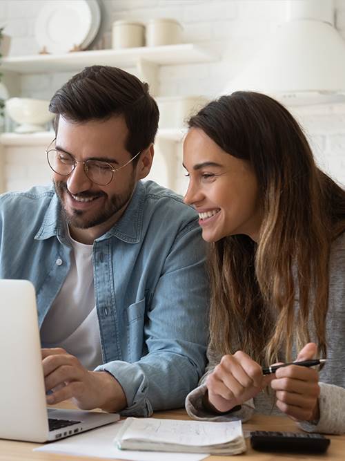 smiling man and woman using laptop to look as savings accounts